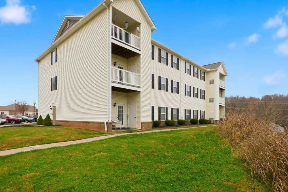 Three-story apartment building with balconies, manicured lawns, and parking area at Norwood Greene Senior Living in Marietta, Ohio
