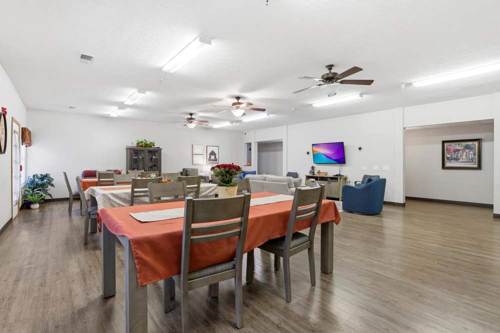 Spacious community room with wood-style flooring and multiple dining tables, bright lighting, and comfortable seating at Norwood Greene Senior Living in Marietta, Ohio