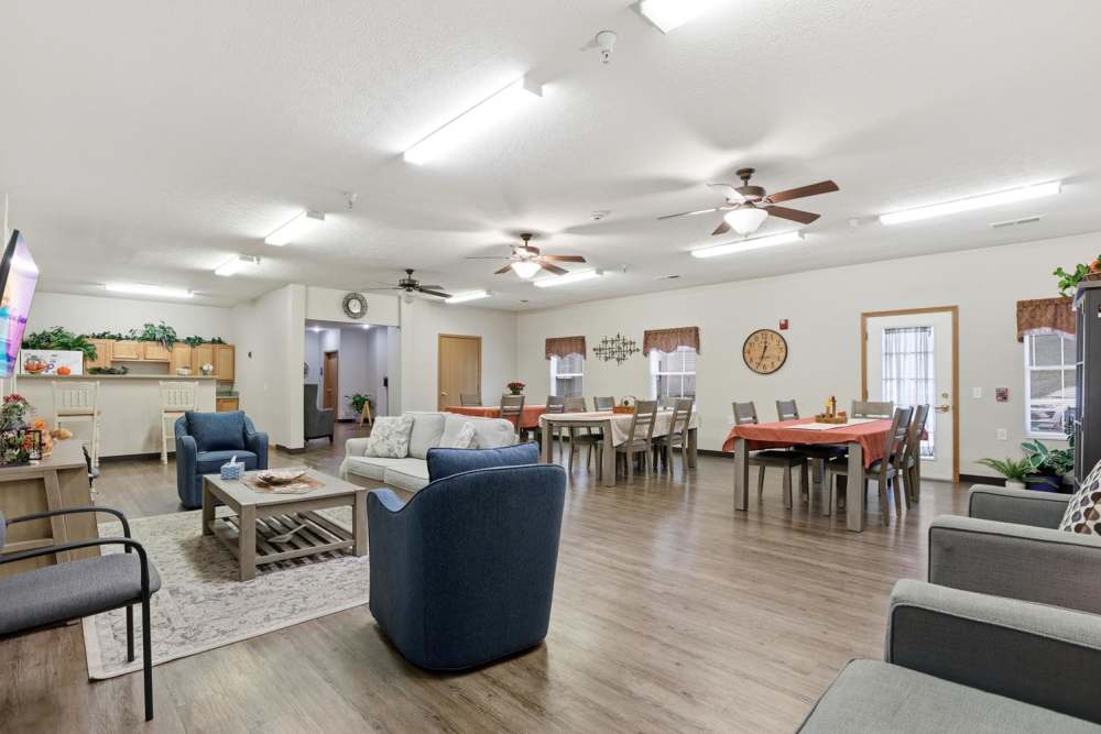 Spacious community lounge with wood-style flooring, comfortable seating, dining area, and open layout at Norwood Greene Senior Living in Marietta, Ohio