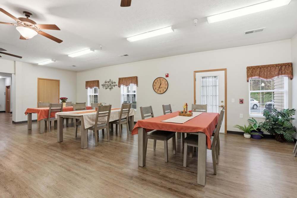 Bright community dining area with wood-style flooring, large tables, and natural light through windows at Norwood Greene Senior Living in Marietta, Ohio