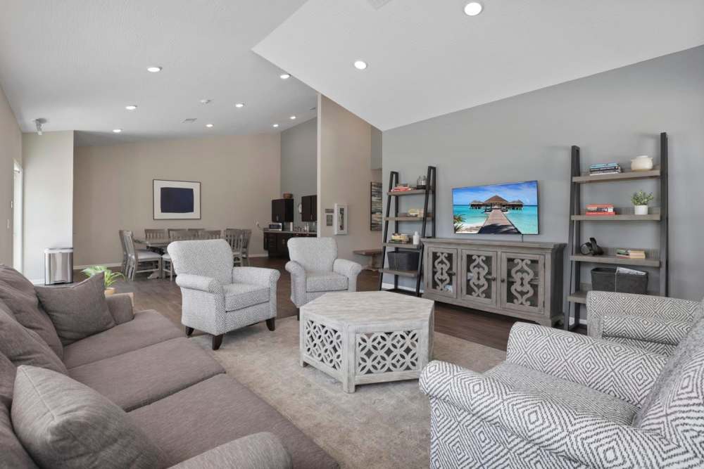 Bright living room with wood-style flooring, cozy sofa, and a television displaying a tropical beach scene at Wheatland Crossing II in Columbus, Ohio