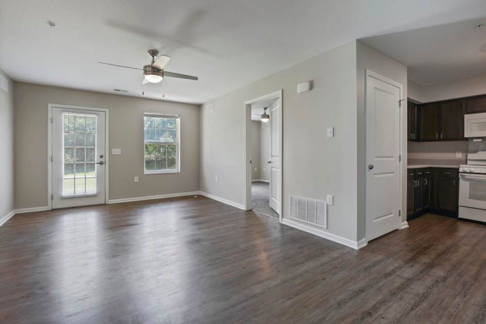 Open layout living space with wood-style flooring and kitchen access, featuring modern appliances and natural light at Wheatland Crossing II in Columbus, Ohio