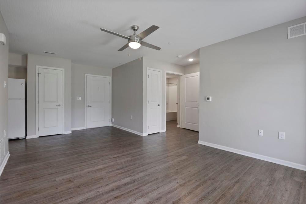 Open layout living area with wood-style flooring and ceiling fan, featuring modern kitchen access at Wheatland Crossing II in Columbus, Ohio