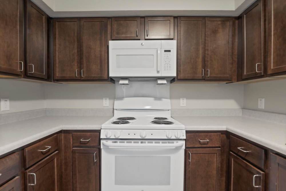 Modern kitchen featuring dark wood cabinets, white appliances, and ample counter space at Wheatland Crossing II in Columbus, Ohio