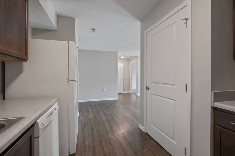 Open layout apartment with wood-style flooring, kitchen appliances, and natural light from the doorway at Wheatland Crossing II in Columbus, Ohio