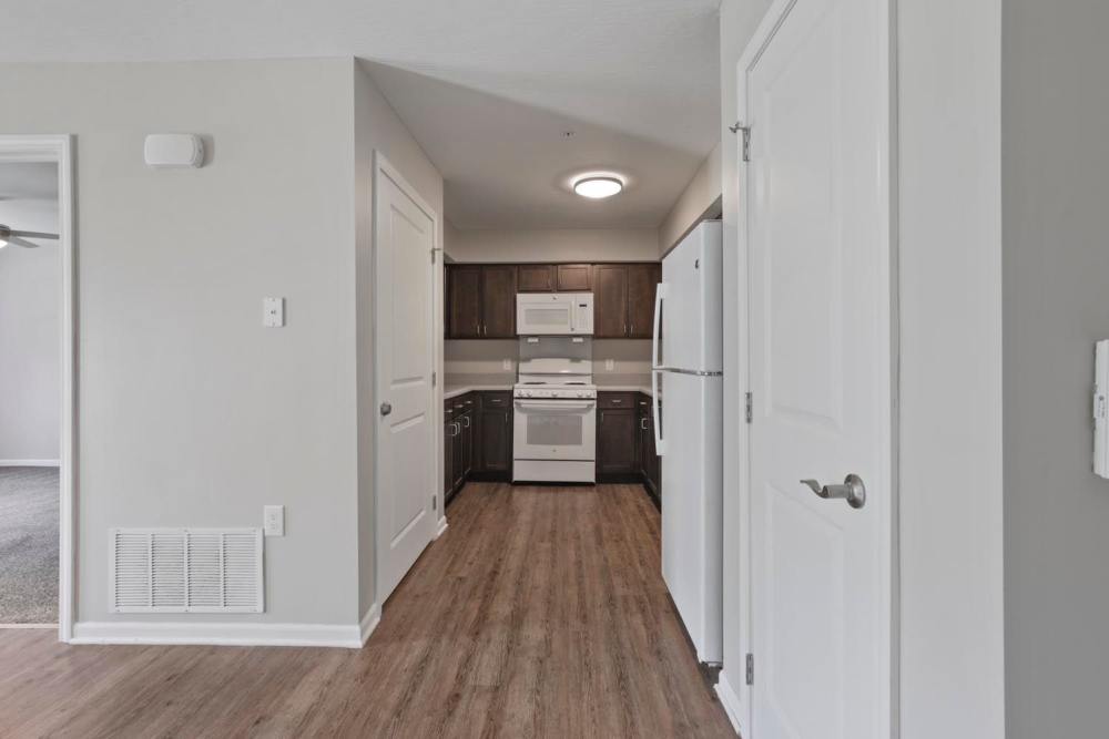 Modern kitchen with stainless steel appliances and wood-style flooring, open layout to living area at Wheatland Crossing II in Columbus, Ohio