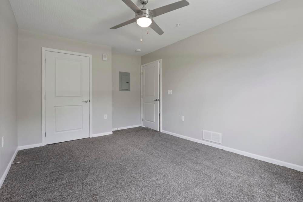 Spacious room with gray carpet, ceiling fan, and two doors leading to adjacent areas at Wheatland Crossing II in Columbus, Ohio