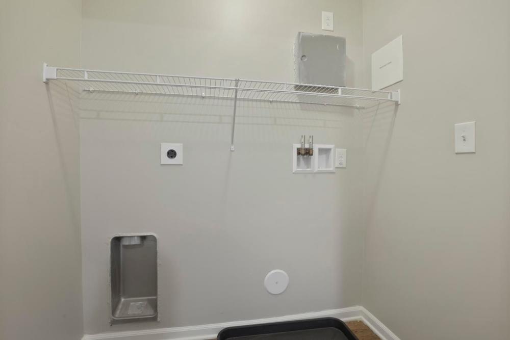 Laundry area with wire shelving and plumbing fittings for washer and dryer at Wheatland Crossing II in Columbus, Ohio