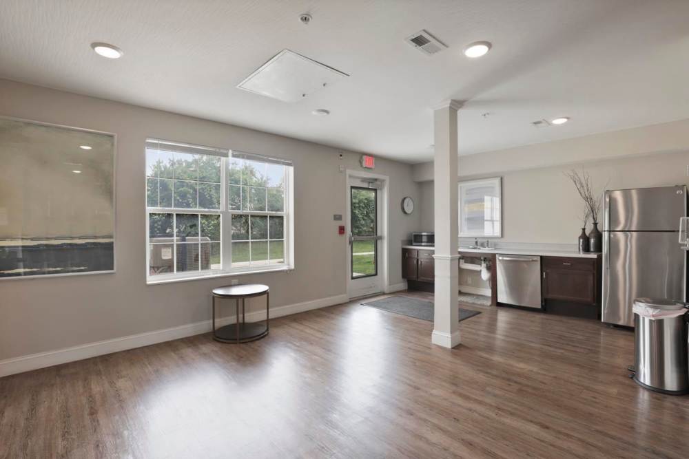 Spacious community room with wood-style flooring and stainless steel appliances in kitchen at Wheatland Crossing II in Columbus, Ohio