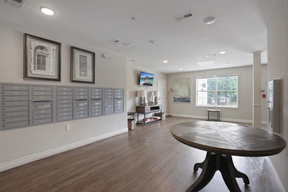 Bright community mailroom with modern decor, wood-style flooring, and a round table for gatherings at Wheatland Crossing II in Columbus, Ohio