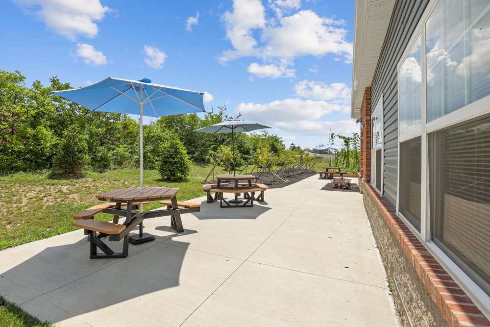 Outdoor patio area with picnic tables and umbrellas surrounded by greenery at Wheatland Crossing II in Columbus, Ohio