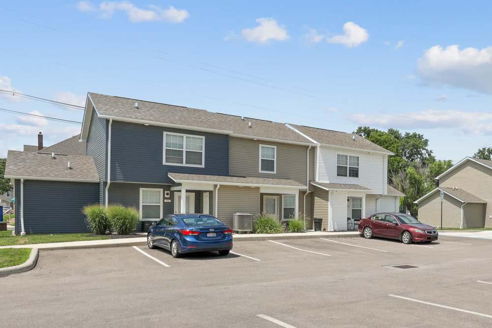 Two-story apartment community with parking, green landscaping, and a clear blue sky at Wheatland Crossing II in Columbus, Ohio