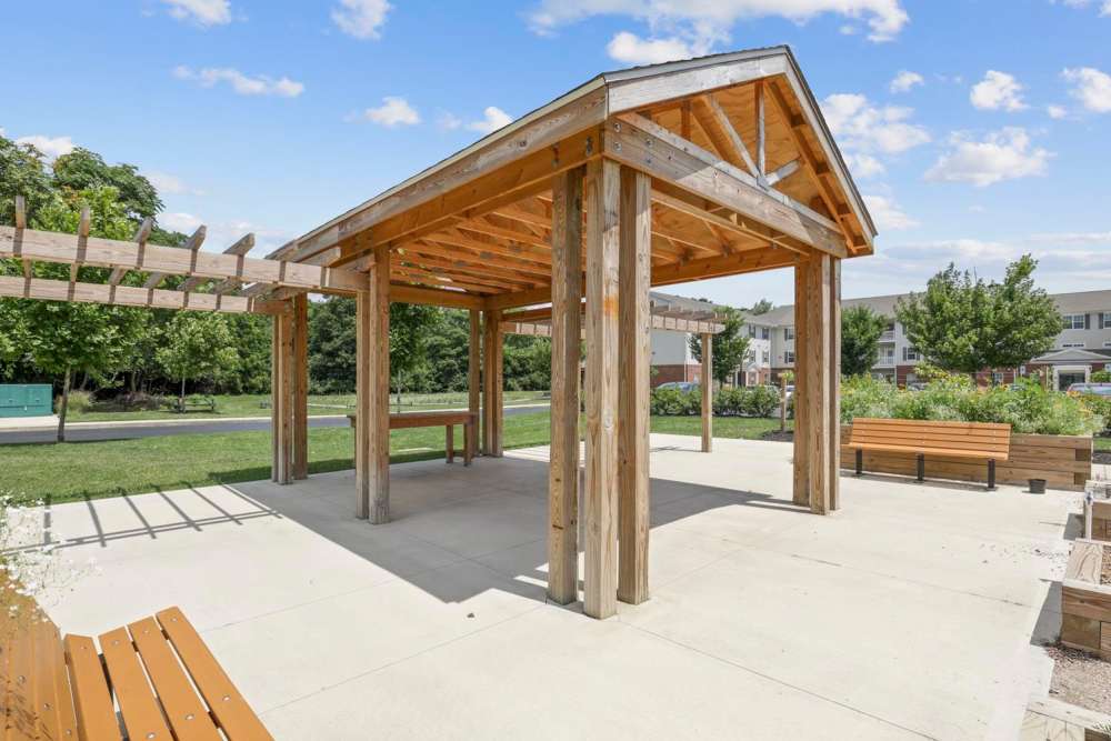 Wooden pavilion with benches surrounded by green landscaping and clear blue sky at Wheatland Crossing II in Columbus, Ohio