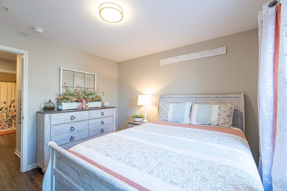 Cozy bedroom featuring a queen bed, wooden dresser, and ambient lighting at White Oak Crossing in Knoxville, Tennessee