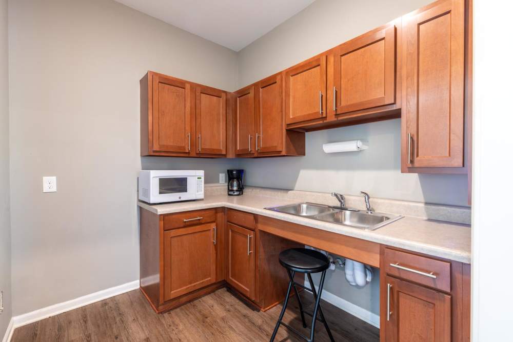 Modern kitchen with wood-style flooring, granite countertops, stainless steel appliances, and ample cabinetry at White Oak Crossing in Knoxville, Tennessee