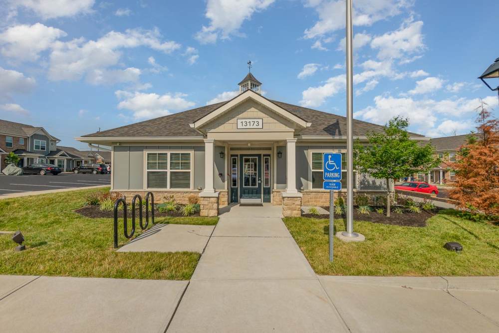 Modern apartment community entrance with landscaped grounds and accessible parking spots at Towne Creek Crossing in Walton, Kentucky