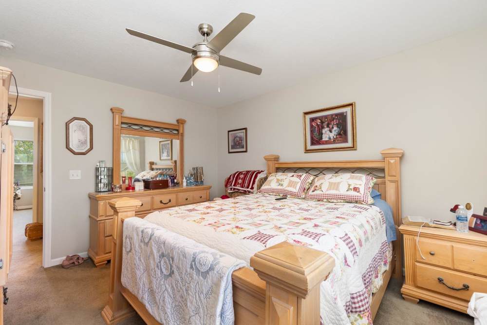 Cozy bedroom with wooden furniture, ceiling fan, and decorative quilt on the bed at Towne Creek Crossing in Walton, Kentucky
