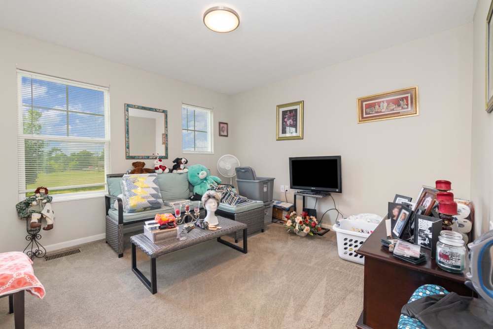 Cozy living room with plush seating, decorative pillows, and bright natural light streaming through windows at Towne Creek Crossing in Walton, Kentucky
