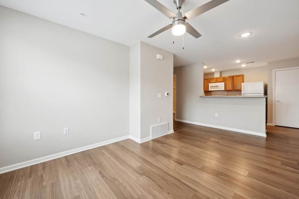 Open layout living space featuring wood-style flooring and kitchen with stainless steel appliances and granite countertops at Woodward Way in East Lansing, Michigan