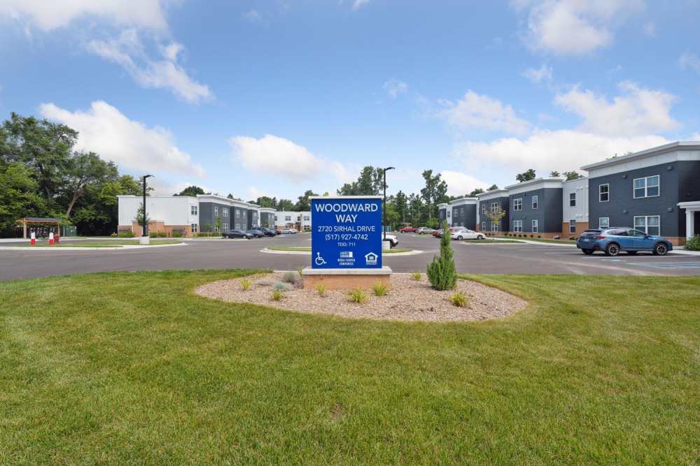 Modern apartment community entrance with landscaped greenery and clear signage at Woodward Way in East Lansing, Michigan