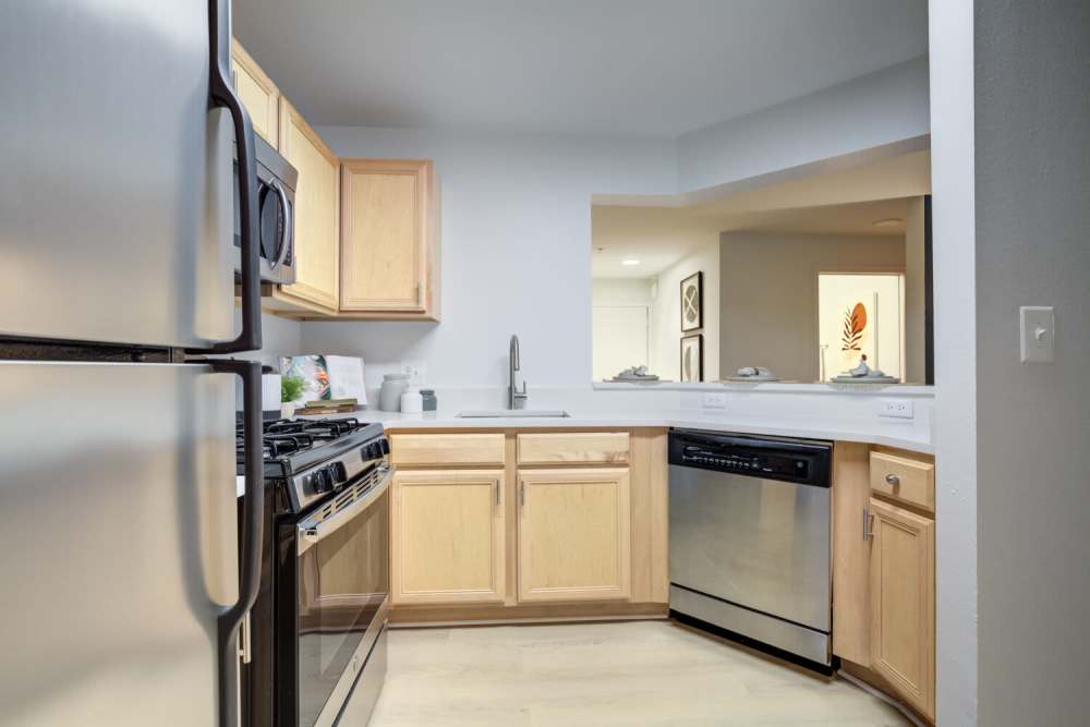 Modern kitchen featuring stainless steel appliances, granite countertops, and light wood-style flooring at J Harbor Park at North Point in Reston, Virginia