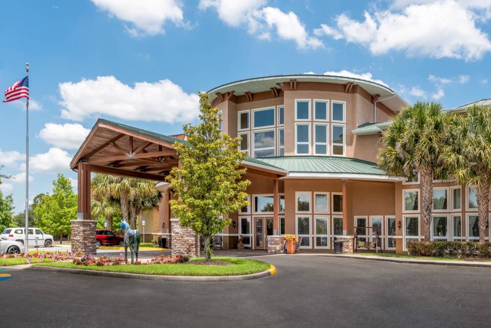 Community exterior view with greenery and american flag at Grand Villa of Ocala in Ocala, Florida