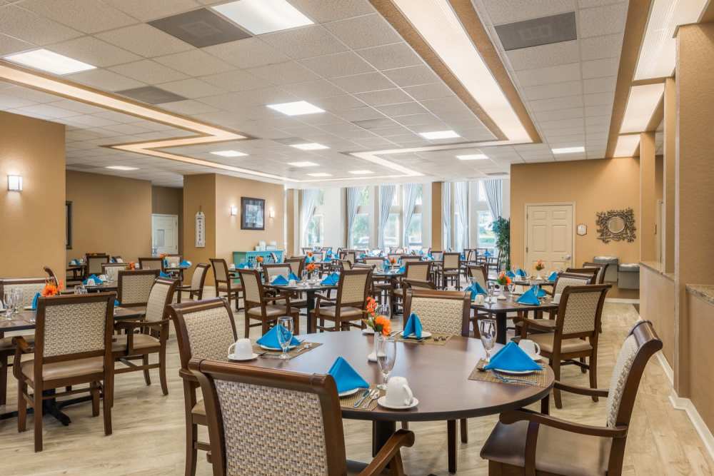Community dining room with round tables and chairs at Grand Villa of Ocala in Ocala, Florida