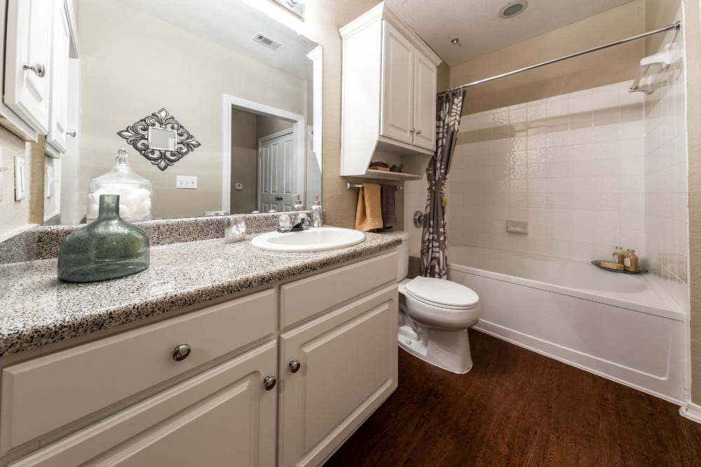 Bright bathroom with wood flooring and bathtub at Marquis at Waterview in Richardson, Texas