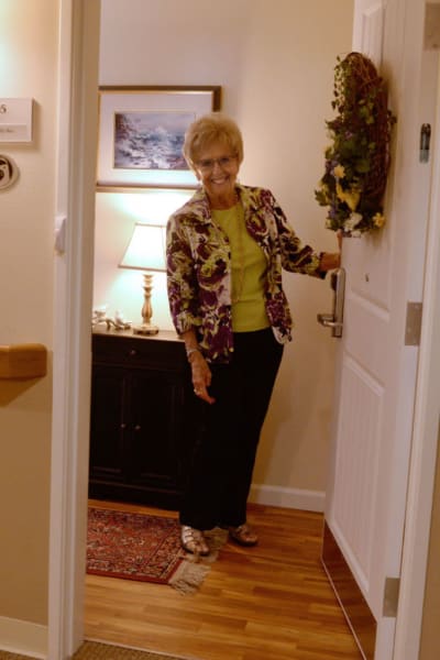 Resident holding the door to her apartment open at Quail Park of Lynnwood in Lynnwood, Washington