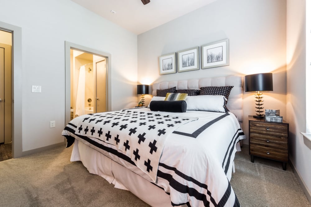Queen size bed in carpeted bedroom with side tables and private bathroom at Marq Uptown in Austin, Texas