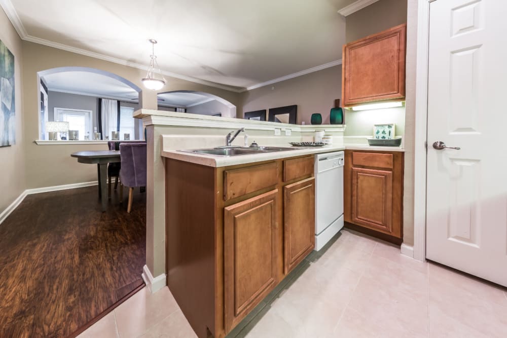 Bright kitchen with white appliances and wood cabinets facing dining area at Marquis at The Cascades in Tyler, Texas
