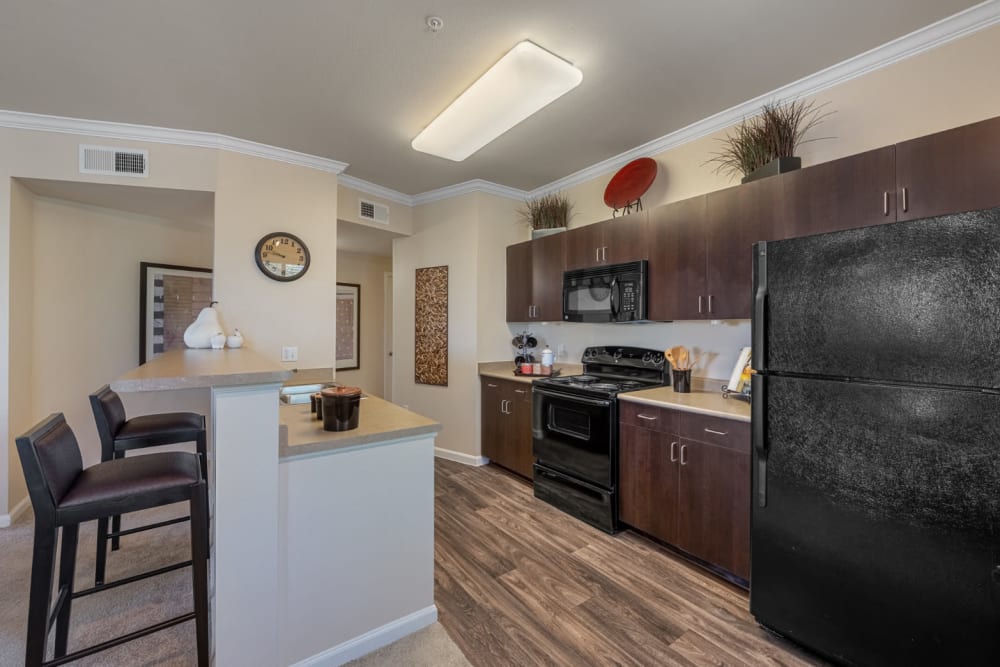 Bright and open kitchen with wood flooring and counter stool chairs at Marquis at Sonoran Preserve in Phoenix, Arizona