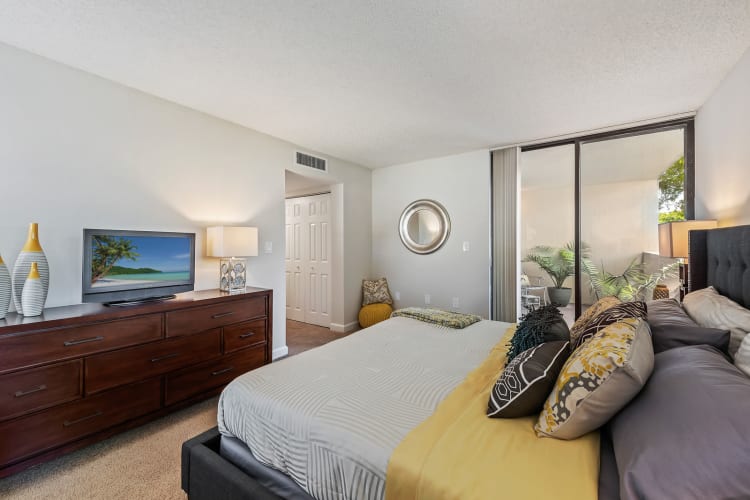 Furnished model bedroom with patio access and lush carpeting at Meadow Walk Apartments in Miami Lakes, Florida