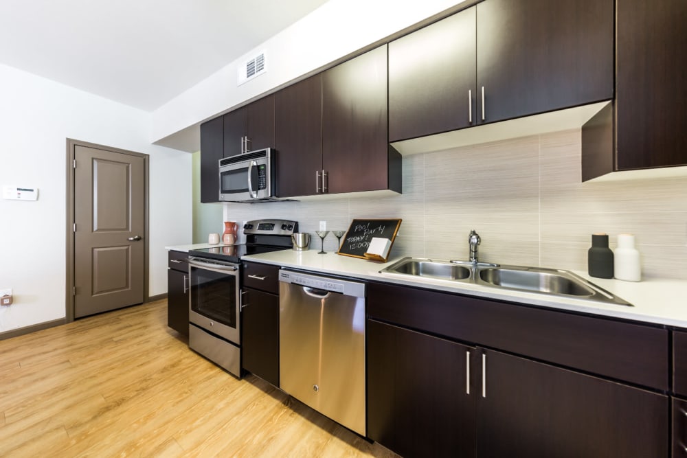 Modern style kitchen with stainless steel appliances and wood flooring and nearby closet at Marquis at Desert Ridge in Phoenix, Arizona