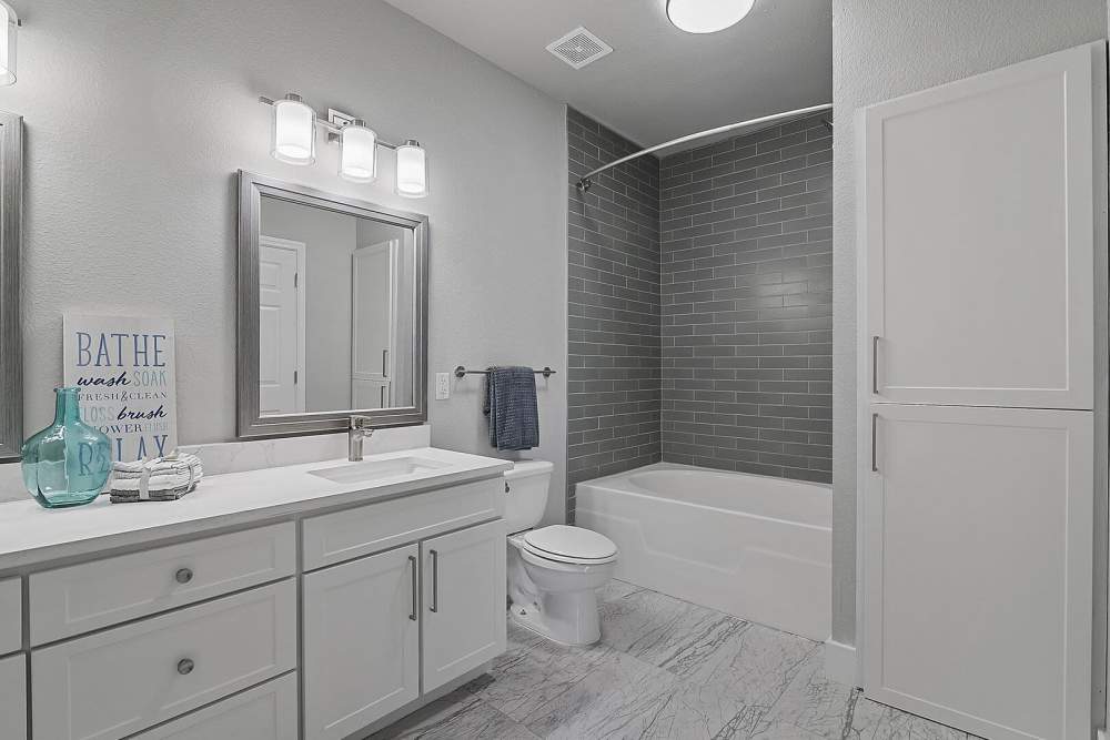 Bright bathroom with vanity light, sink and bathtub at Florence in Houston, Texas