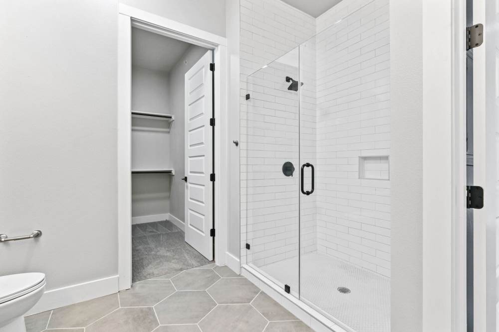 Bright bathroom with commode, glass shower and hard flooring at Kade in Dallas, Texas