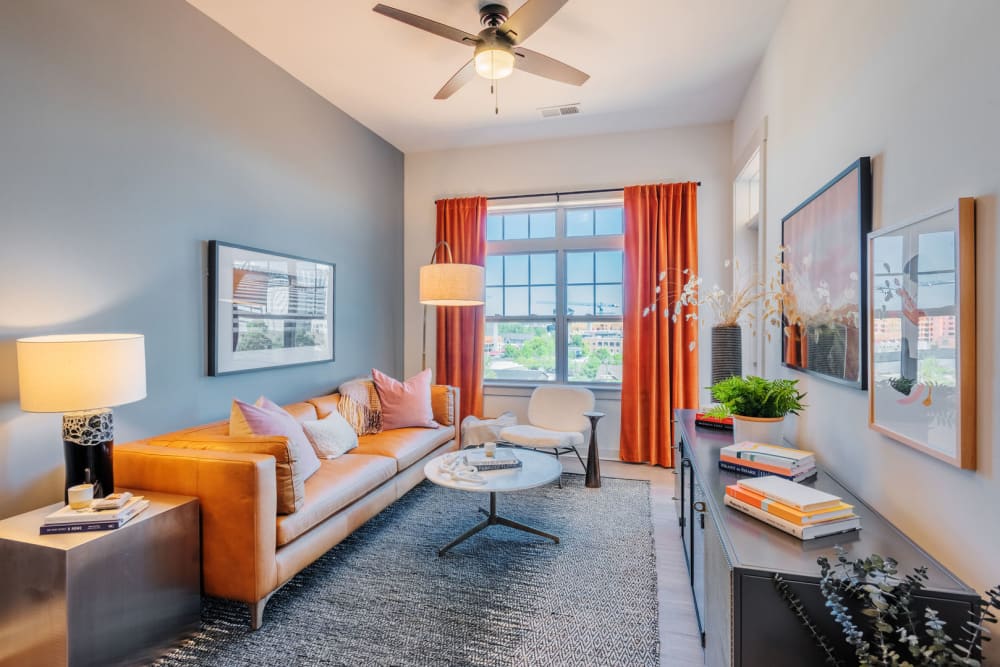 Living room with a ceiling fan and wood-style flooring in a model home at District Flats in Charlotte, North Carolina