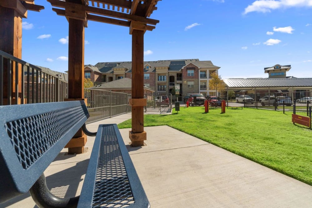 Bench under a pergola in the fenced onsite dog park at Auberge of Burleson in Burleson, Texas