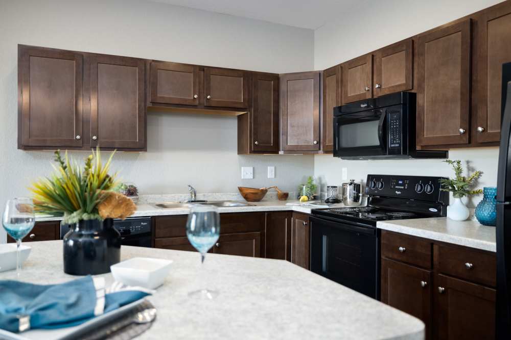 Kitchen with black appliances and wooden cabinets at University Commons in Williston, North Dakota