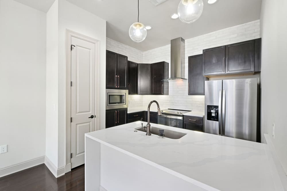 Kitchen with waterfall sink and stainlesss-steel appliances at Domain Memorial in Houston, Texas