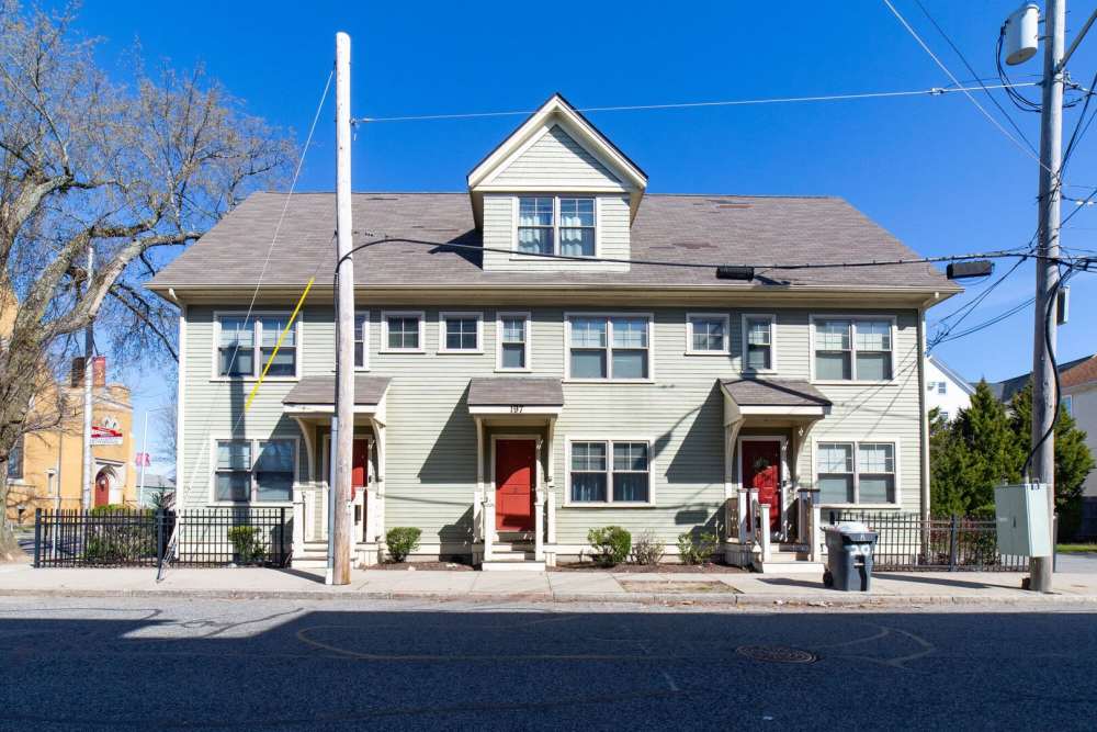 Street view of a community apartment complex with visible parking spaces at One Neighborhood Builders in Providence, Rhode Island
