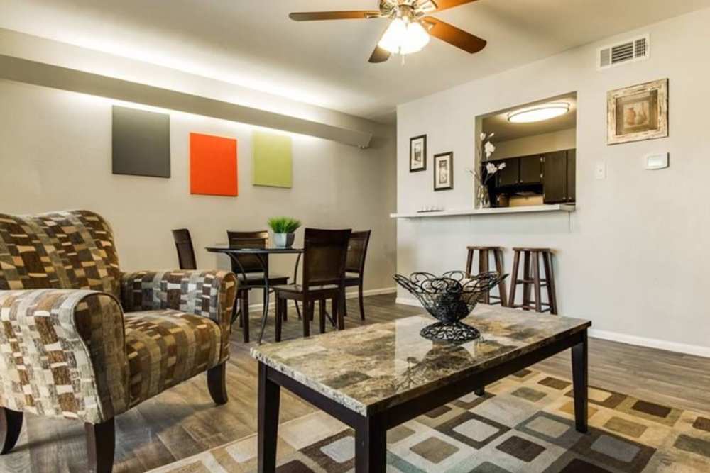 Living room with chair, coffee table and ceiling fan with access to dining room and kitchen at Alamo Estates in San Antonio, Texas