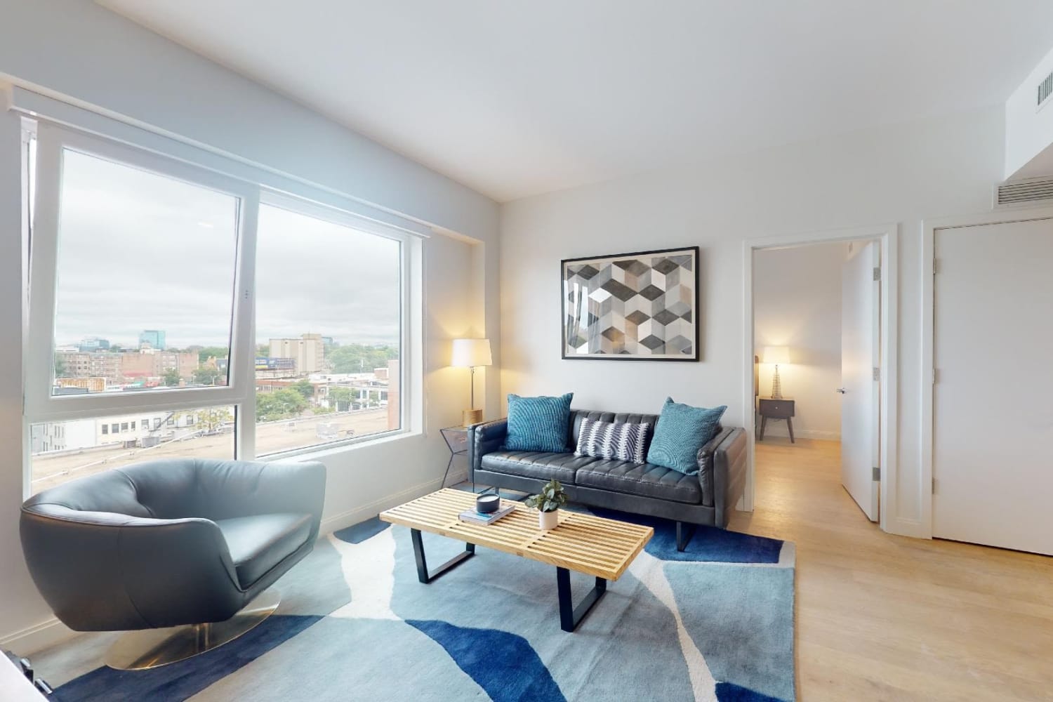 Modern furnishings and hardwood-style flooring in a model home's living space at 55 Brighton at Packard Crossing in Boston, Massachusetts