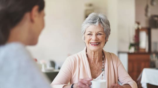 Adult day health senior chatting with a caregiver over tea at Cascade Park Adult Day Health in Tacoma, Washington 