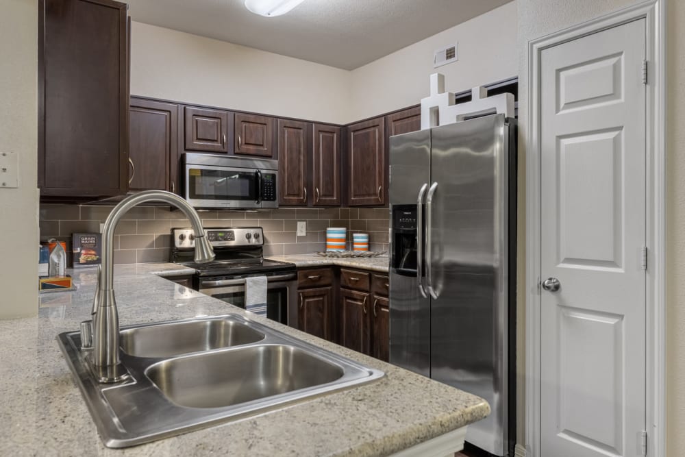 Modern kitchen with granite counters and stainless steel appliances at Marquis at Kingwood in Kingwood, Texas