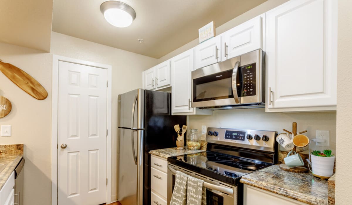 Fully equipped kitchen with granite countertops stainless steel appliances like a refrigerator and drawer microwave at UTE Creek Apartments in Longmont, Colorado