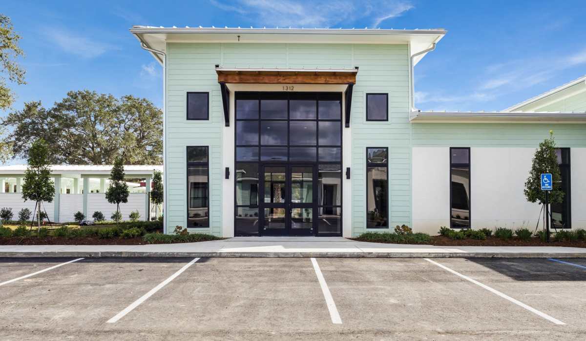 Modern apartment community entrance with large windows and landscaped greenery at Lakewood Villas in Bossier City, Louisiana