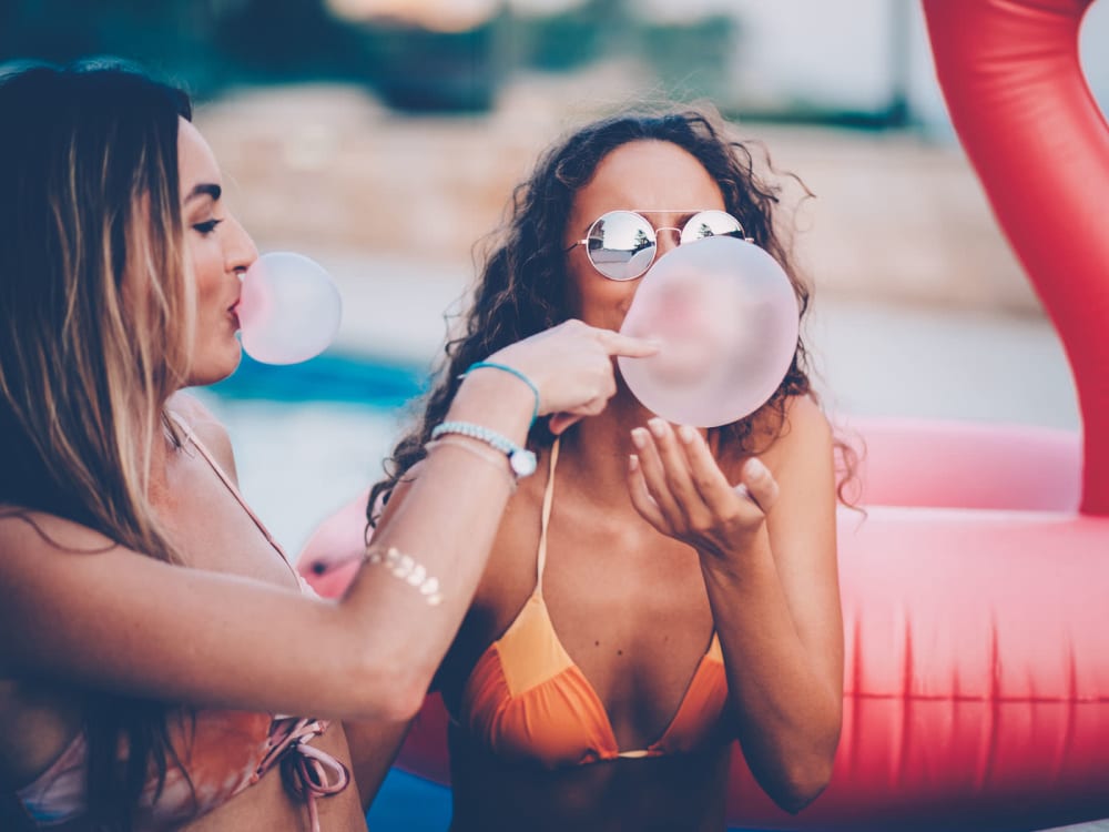 Friends blowing bubbles with gum on the edge of the pool at The Piedmont in Tempe, Arizona