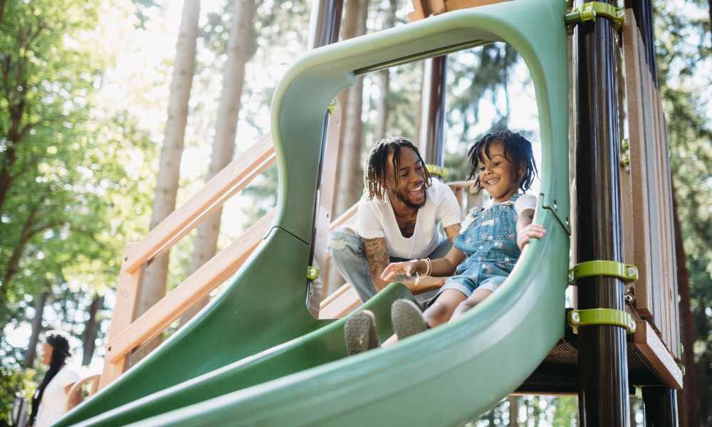Kid playing with father on the slide in playground at Valley Park Subdivision in Jackson, Mississippi