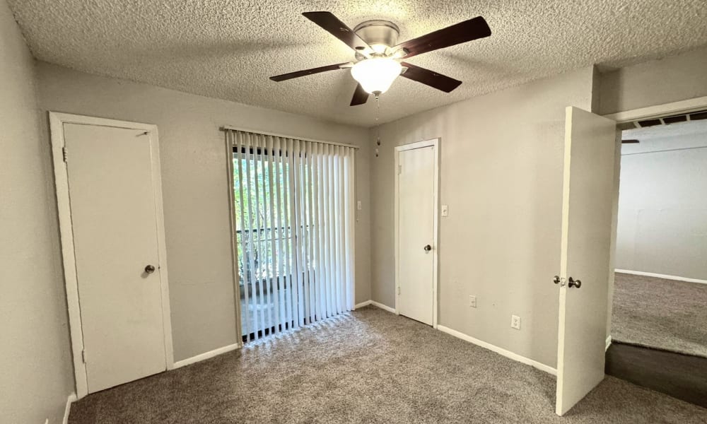 Bedroom with access to the patio and a ceiling fan at Santa Fe Apartments in Dallas, Texas